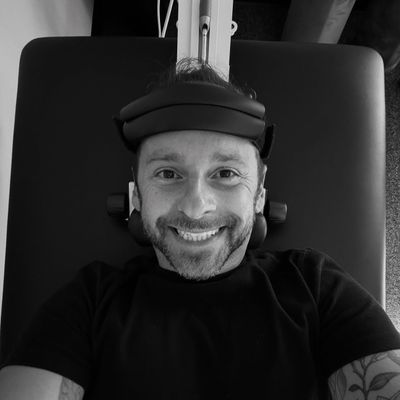 Black and white photo of David Estis lying on a chiropractic table smiling up at the camera
