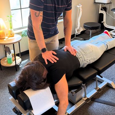 Woman lying on chiropractic table at Next Level Chiropractic in Centennial, CO receiving an adjustment to her spine