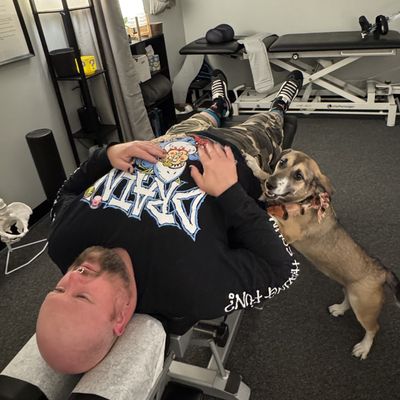 Man lying on chiropracti table with his puppy