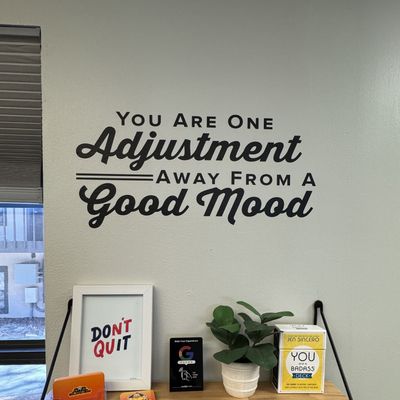 Wall decal at the Next Level Chiropractic office reading: You are just one adjustment away from a good mood