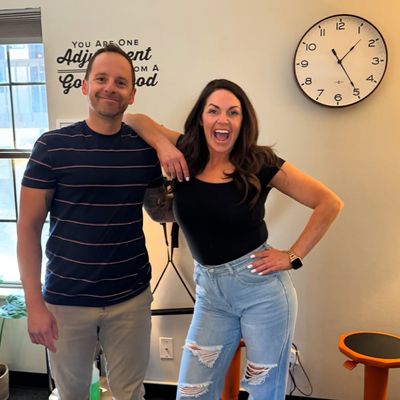 Chiropractor Dr. David Estis posing for the camera at the Next Level Chiropractic office in Centennial, CO with a happy, pain-free patient